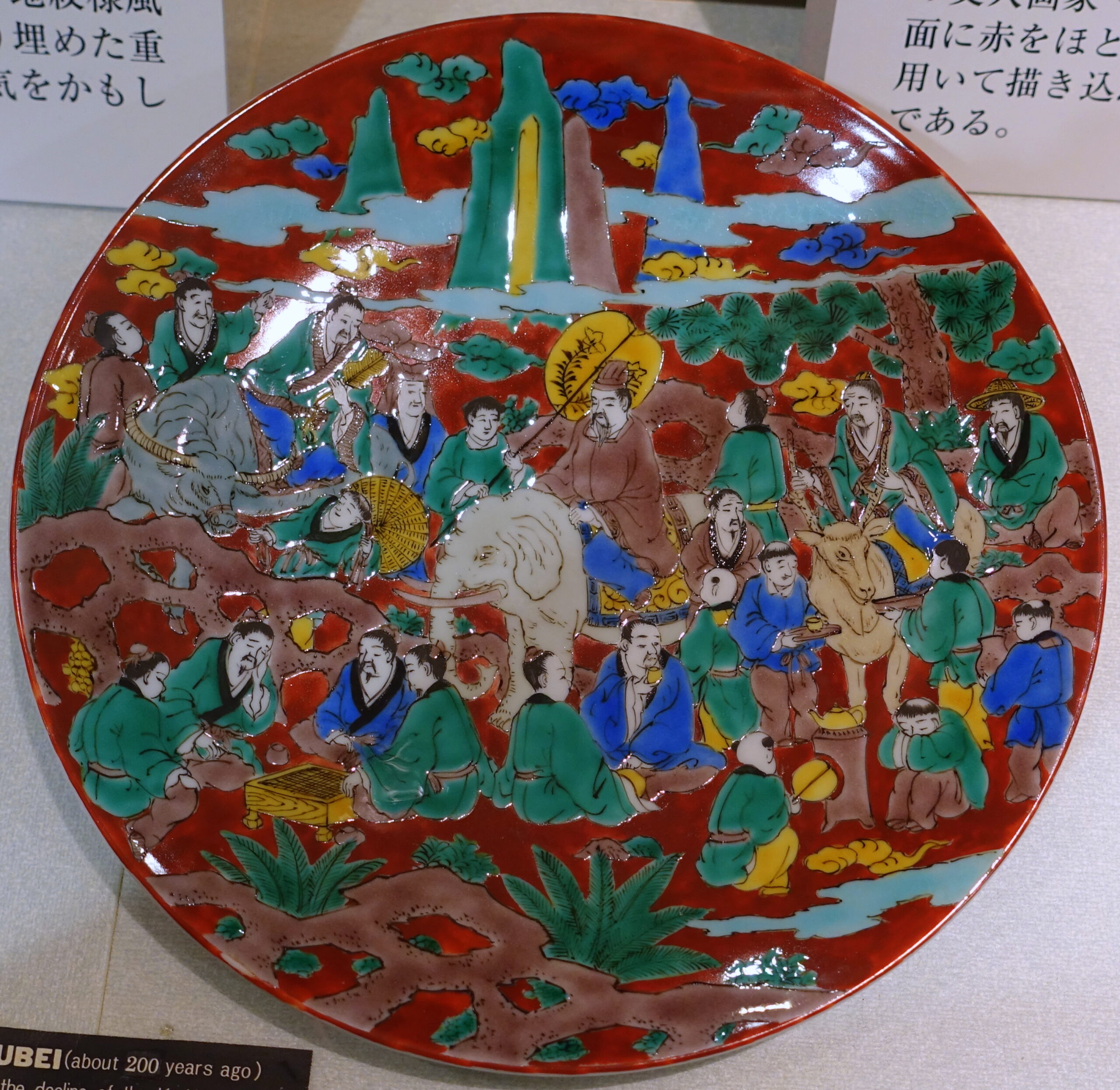 Saiko-Kutani dish in Mokubei style — the Kyoto-influenced 1807 revival, with red-ground Chinese scenes