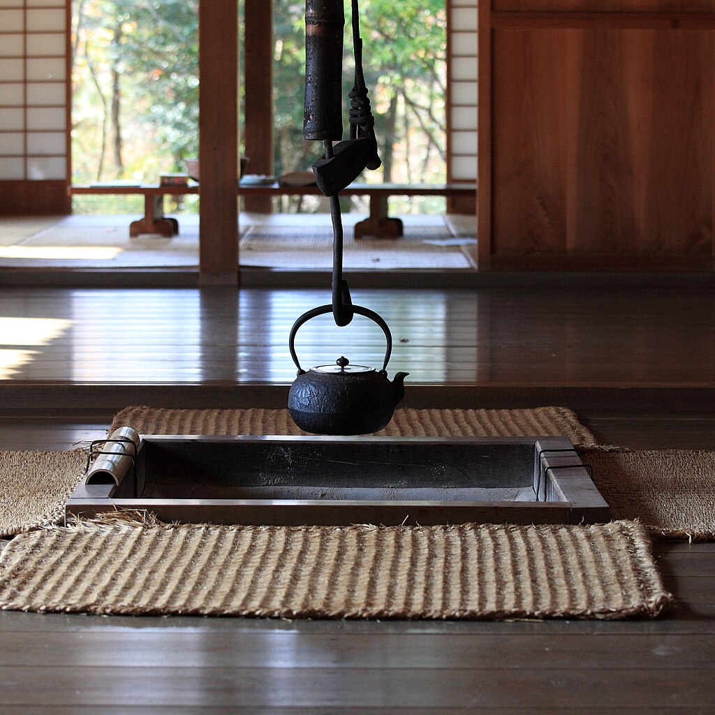 A cast-iron tetsubin hanging over an irori sunken hearth in a traditional Japanese farmhouse