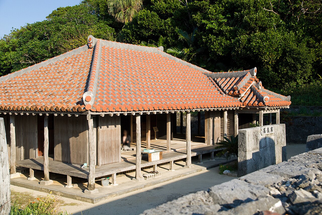 Traditional Okinawan house with red clay-tile roof under bright subtropical sky
