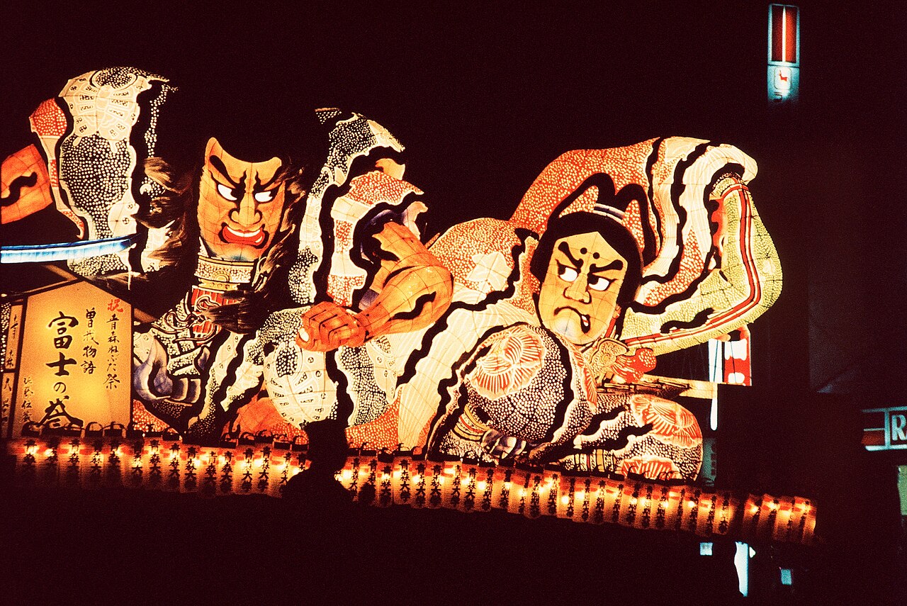 Illuminated Nebuta festival float glowing over a summer crowd in Aomori
